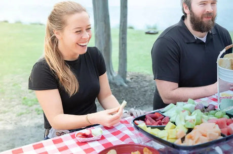 1/4 lb. Red Check Compostable Food Tray held with customers eating from it